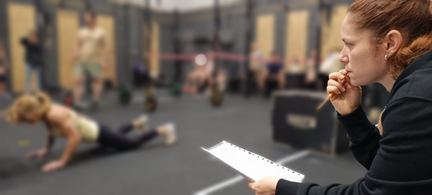 Una jueza sigue con la hoja de puntuación el trabajo de una atleta en el suelo