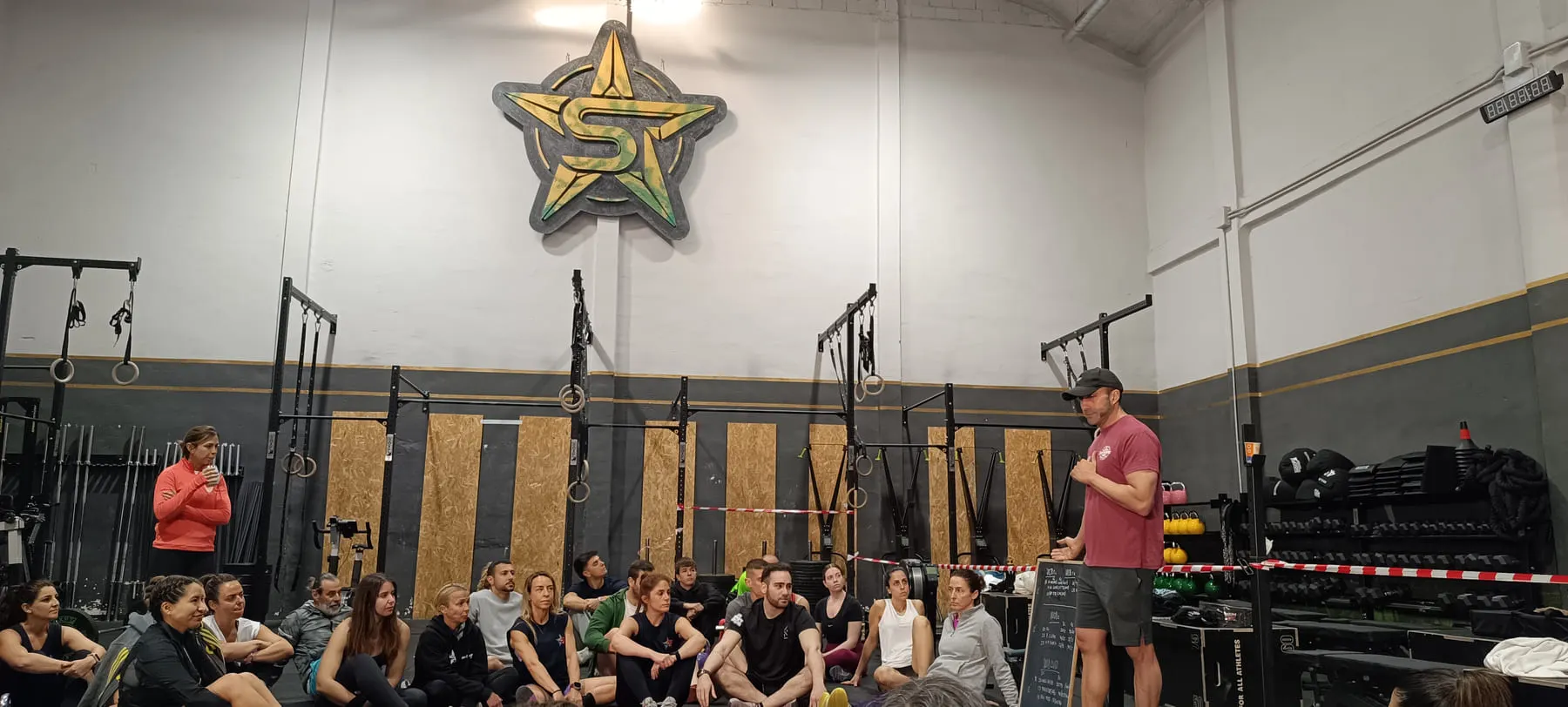 La sala entera del box, con la estrella del logo en la pared y la clase sentada escuchando