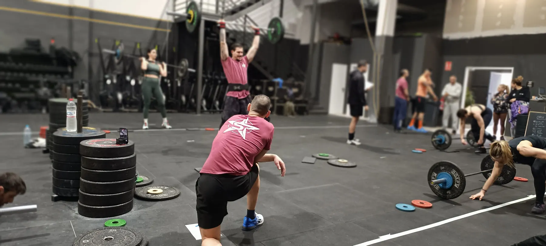 Momento del WOD con una barra bloqueada en alto y toda la sala en movimiento